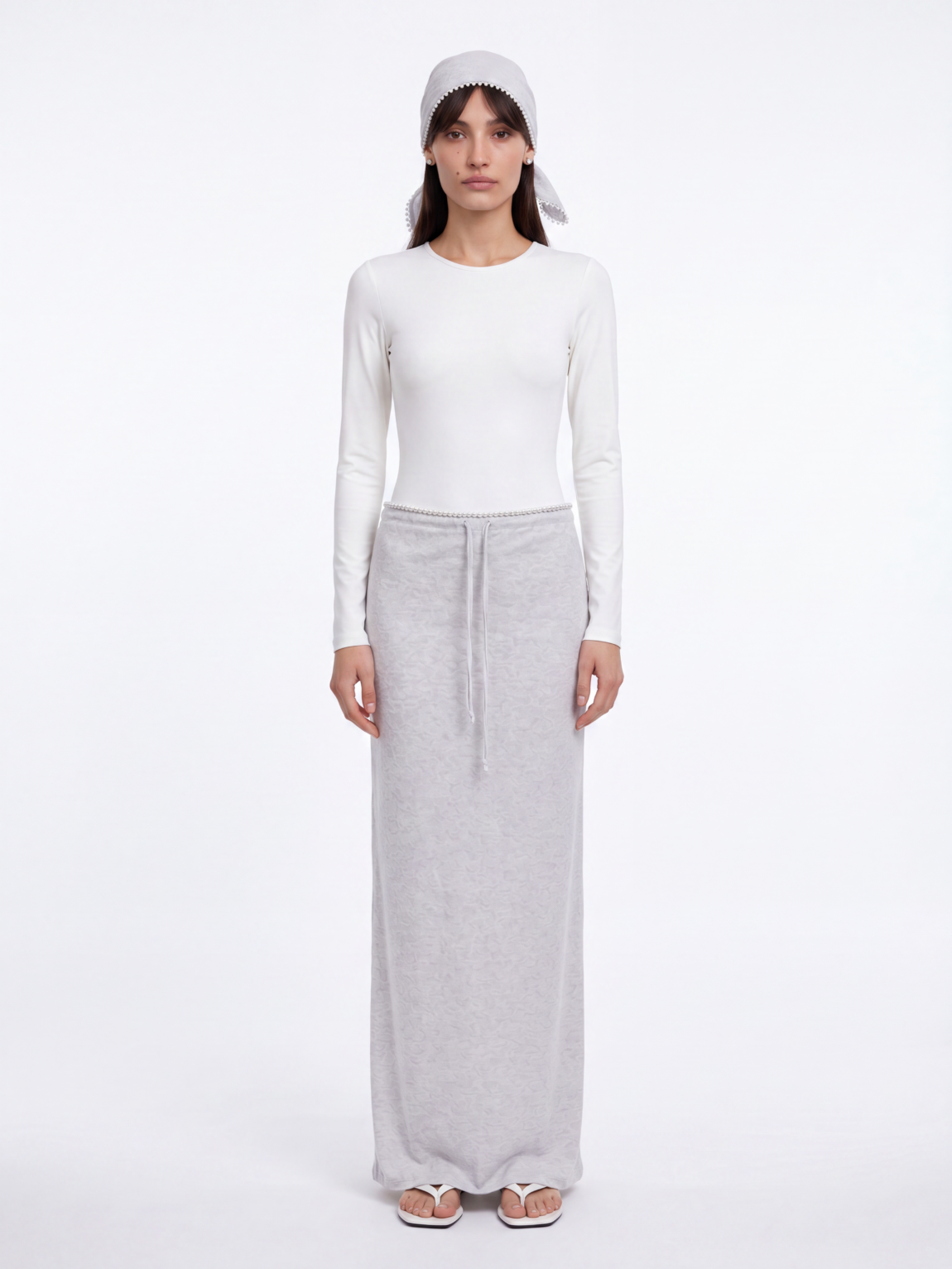 Bella wearing ESPRESSO light gray skirt and headscarf set with white Skill bodysuit and white TOTEME sandals