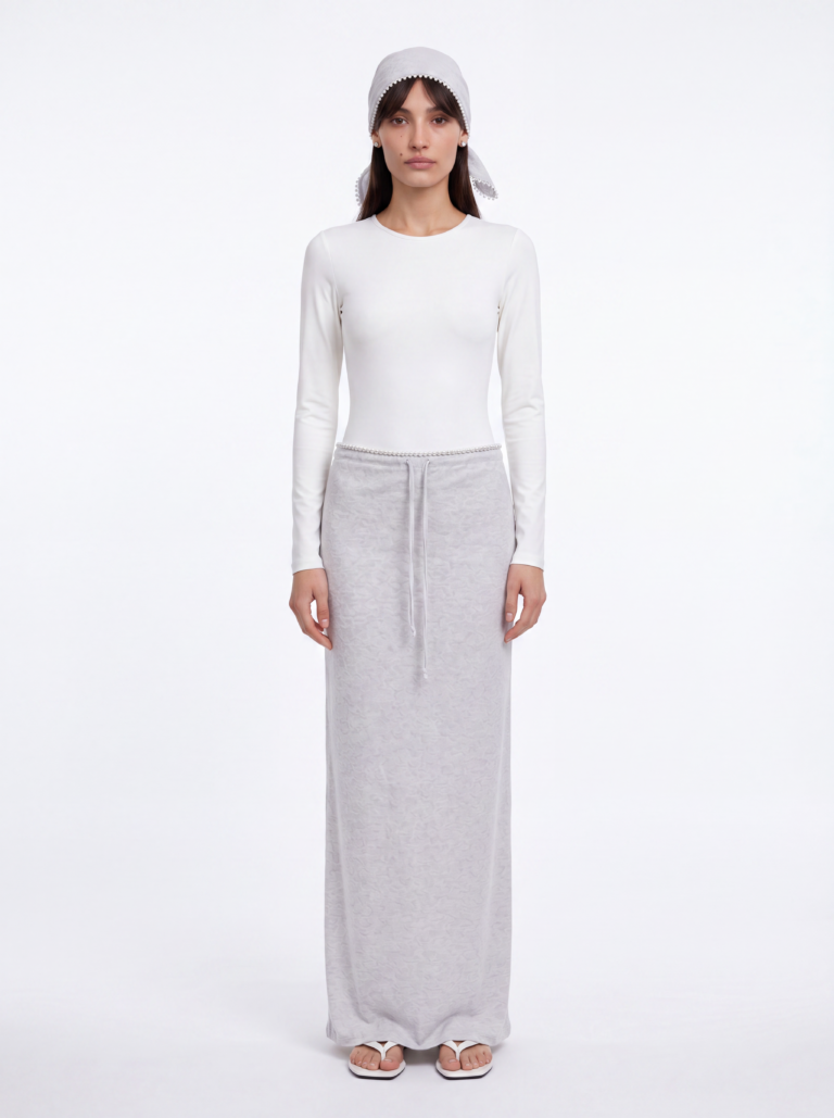 Bella wearing ESPRESSO light gray skirt and headscarf set with white Skill bodysuit and white TOTEME sandals